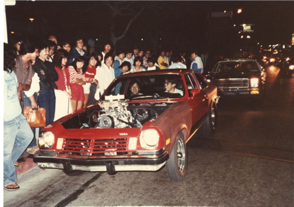 Street racers Tod Kaneko and David Eguchi, inside of Glen Kuwata's Chevrolet Vega, during a Nisei Week cruise, Little Tokyo, 1982. Credit: Courtesy of Tod Kaneko.